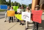 Residents outside Town Hall with protest signs