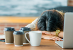 Tired woman resting against desk