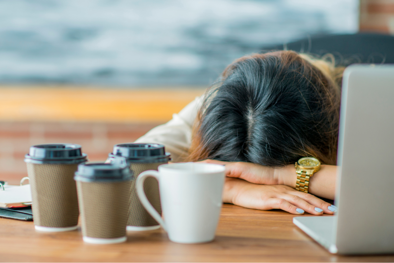Tired woman resting against desk